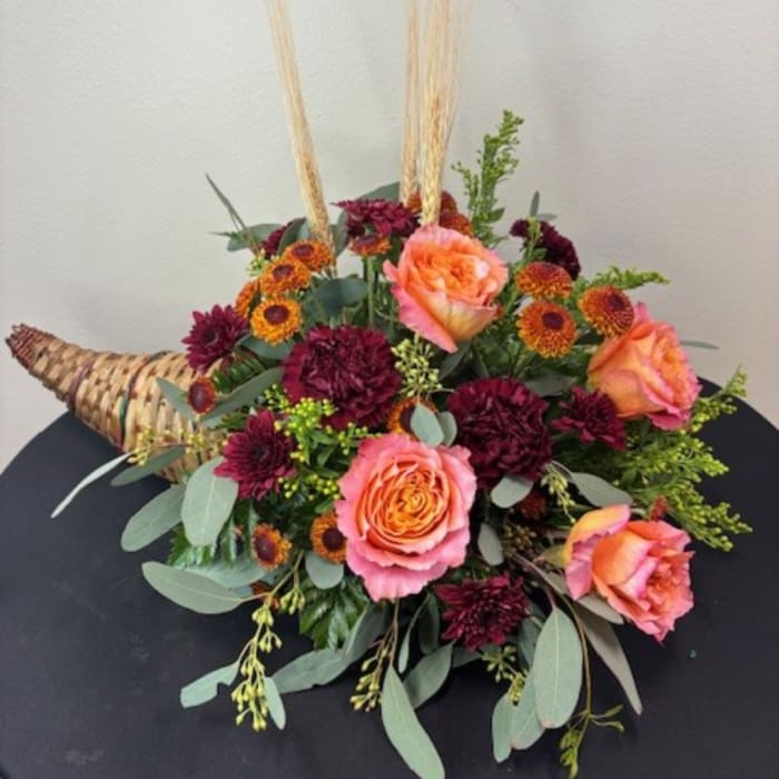 Peach roses and burgundy mums in a woven horn-shaped basket