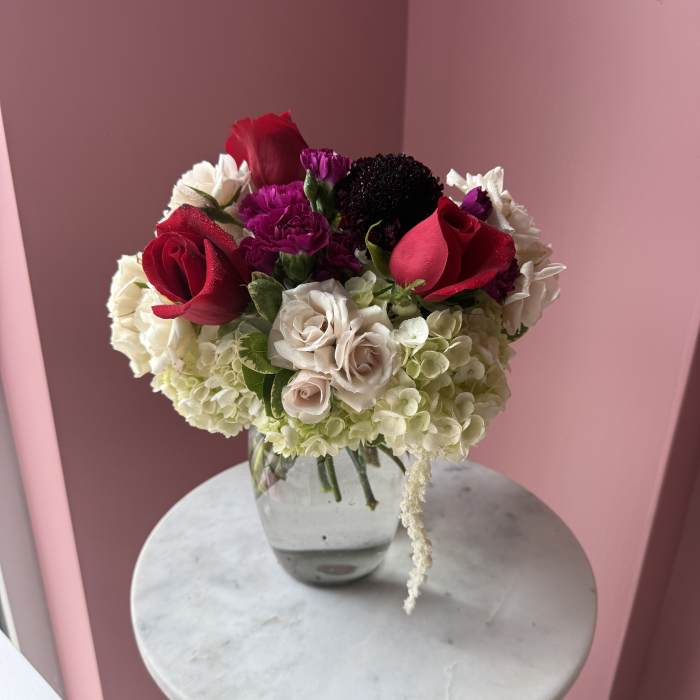 Bouquet of red roses, white hydrangeas, and purple carnations in a glass vase