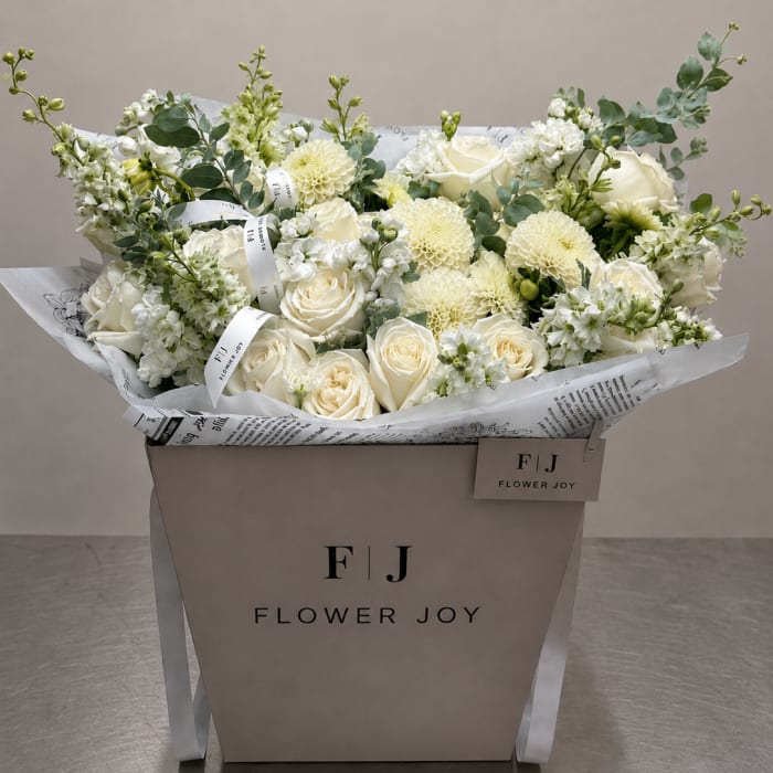 Cream and white bouquet of roses and dahlias in a branded box