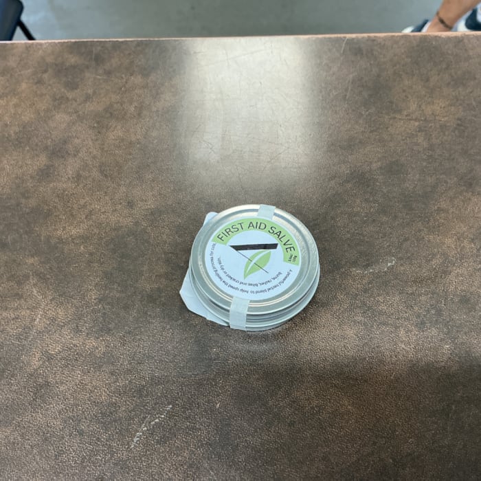 Small tin labeled first aid salve on a table