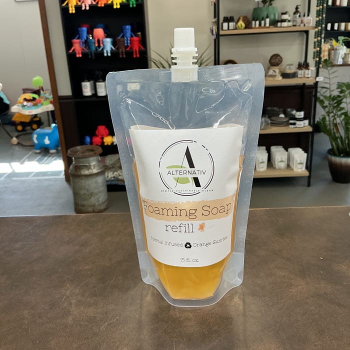 Foaming soap refill pouch with orange liquid on a counter