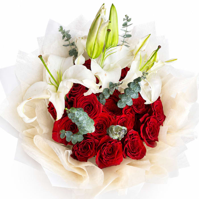 Bouquet of red roses and white lilies wrapped in cream paper