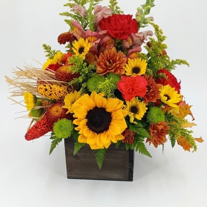 Autumn floral arrangement with sunflowers and mums in a dark wooden box