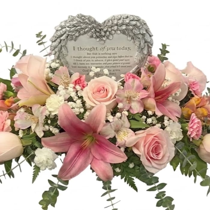 Pink lilies and roses arranged around a heart-shaped memorial plaque
