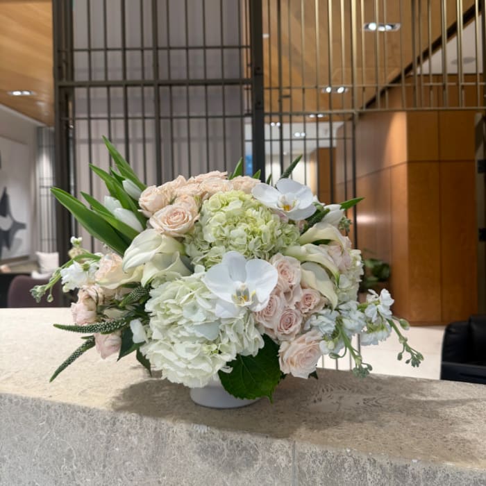 White and blush floral arrangement in a low white bowl vase