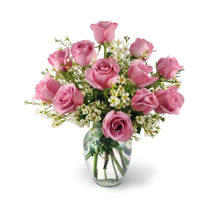 Pink roses arranged in a clear glass vase with small white filler flowers