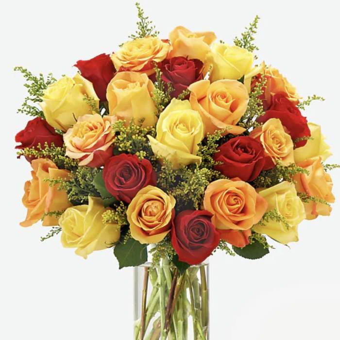 Bouquet of red, yellow, and orange roses in a clear glass vase