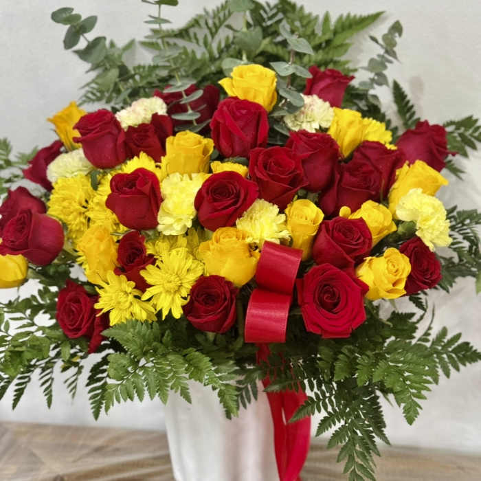 Bouquet of red and yellow roses with yellow chrysanthemums in a white vase