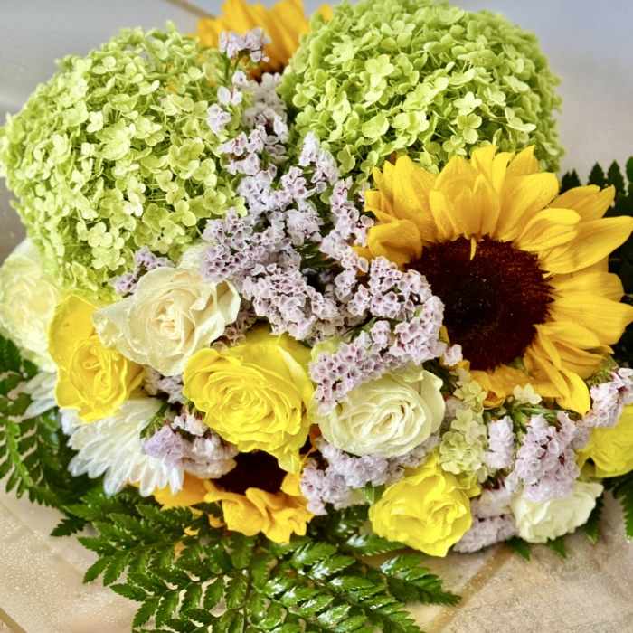 Bouquet of yellow sunflowers, cream roses, and green hydrangeas