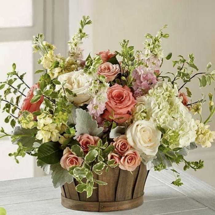 Mixed bouquet of pink and white flowers in a wooden basket