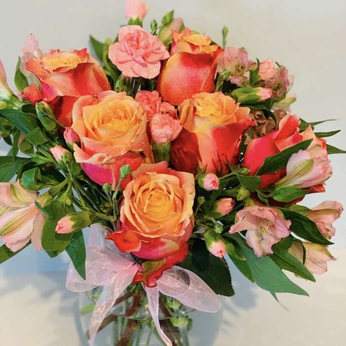 Bouquet of orange and pink roses with alstroemeria in a glass vase