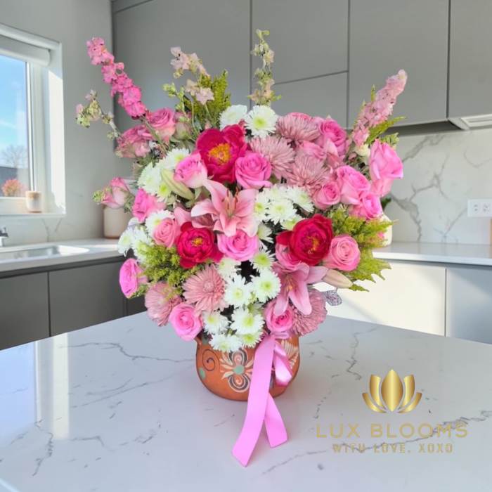 Pink and white mixed flower arrangement in a decorative vase with a ribbon