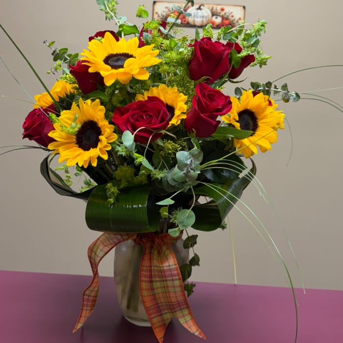 Bouquet of red roses and yellow sunflowers in a vase