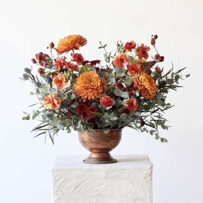 Orange and red mixed bouquet in a copper vase