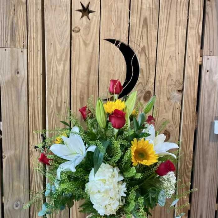 Bouquet of red roses, white lilies, and yellow sunflowers in a glass vase