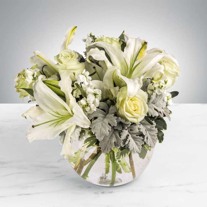 White lilies and roses arranged in a clear glass vase