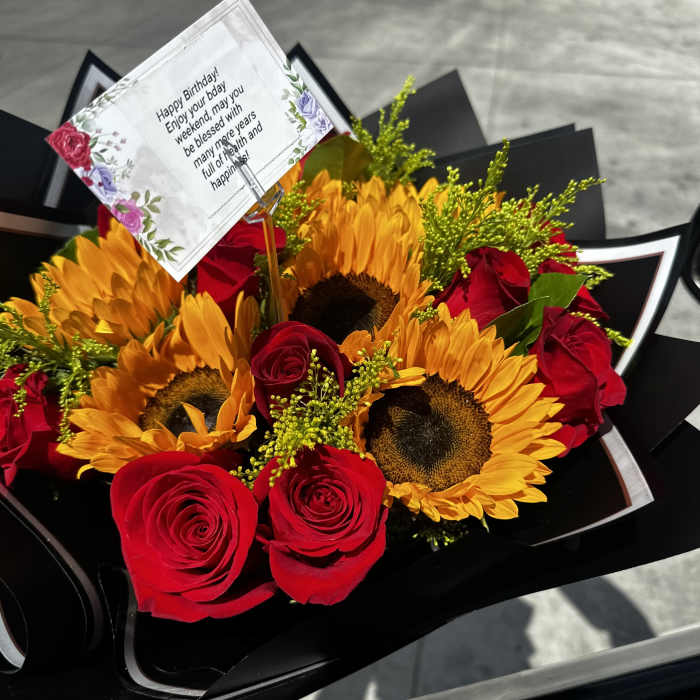 Bouquet of red roses and sunflowers with a birthday card