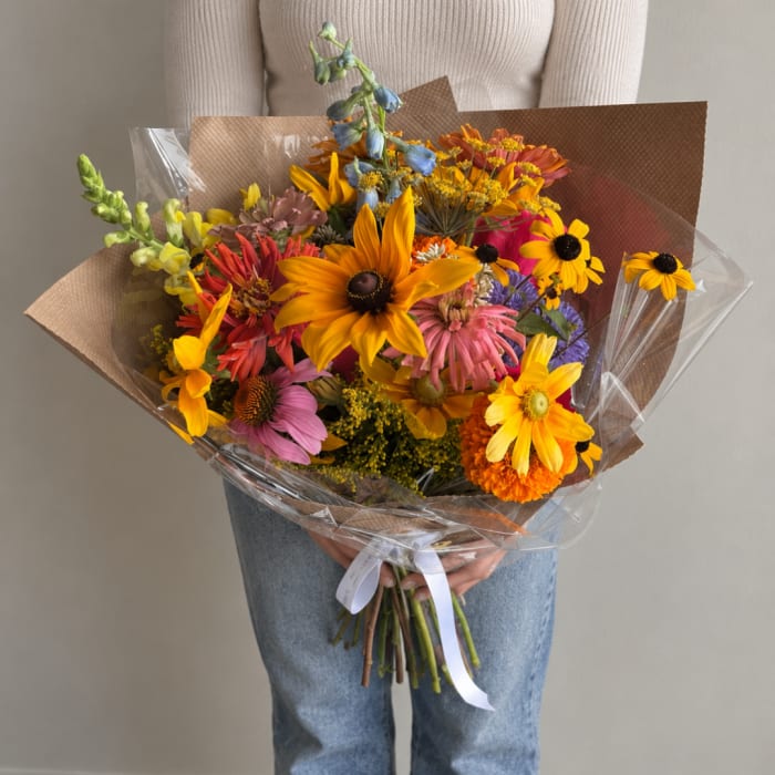 Colorful mixed bouquet with sunflowers and daisies wrapped in brown paper
