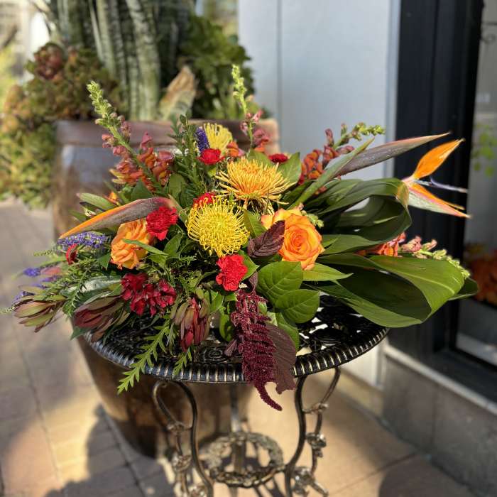 Colorful mixed bouquet with orange roses and yellow blooms on a metal table