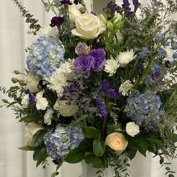 Mixed bouquet in a white vase with blue, purple, and white flowers