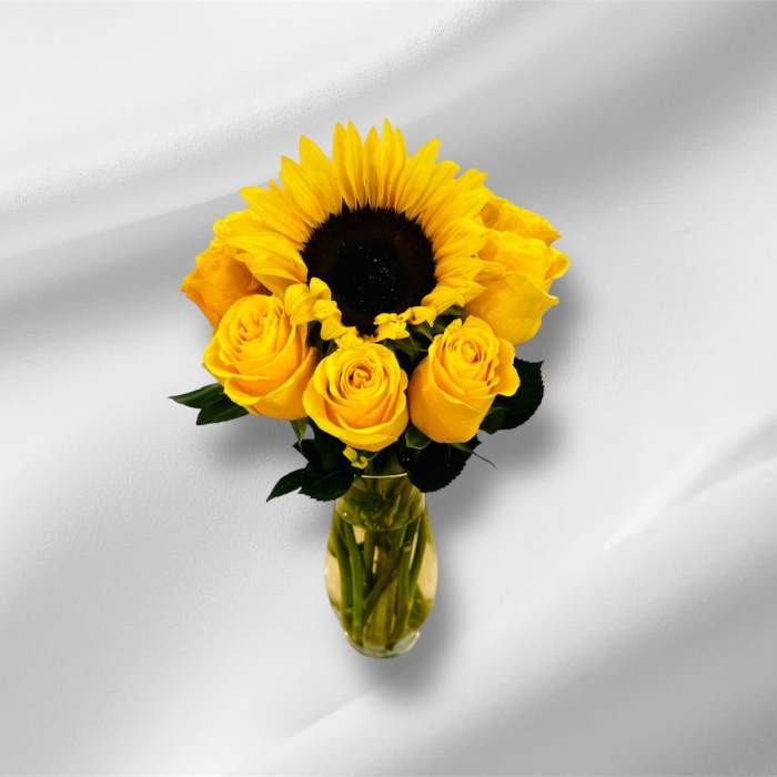 Small vase arrangement with a large yellow sunflower and yellow roses.