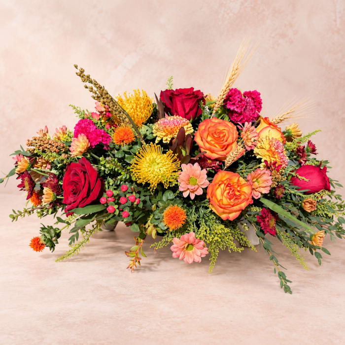Low floral arrangement with red and orange roses and mixed blooms