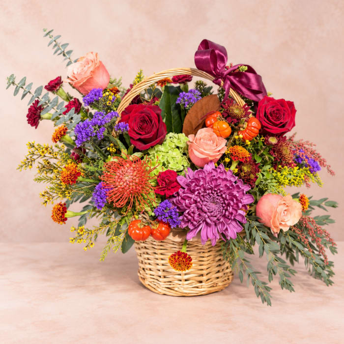 Mixed flower basket with roses, chrysanthemums, and a purple ribbon