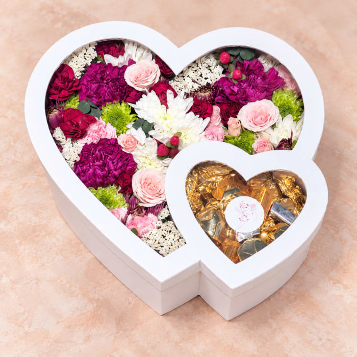 Heart-shaped flower box with pink, white, and magenta blooms and gold chocolates