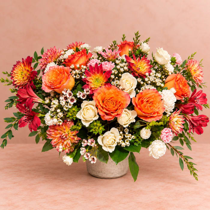 Colorful mixed bouquet in a small vase with orange, pink, and white blooms
