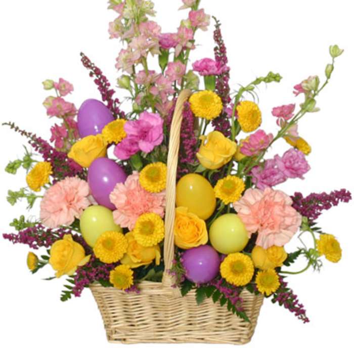 Basket arrangement with yellow roses, pink carnations, snapdragons, and colorful Easter eggs.