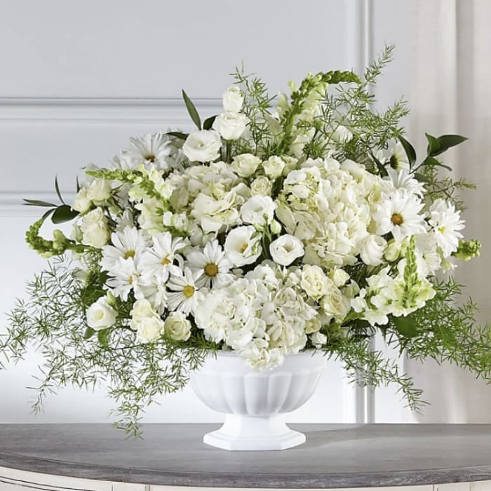White floral arrangement in a white pedestal vase