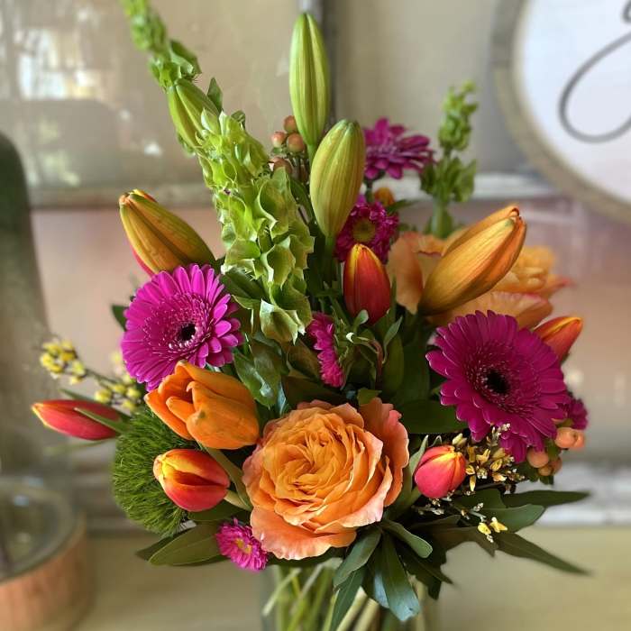 Colorful bouquet of tulips, roses, and gerbera daisies in a glass vase