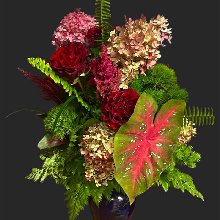 Red roses and pink hydrangeas in a dark glass vase