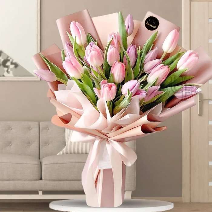 Pink tulip bouquet wrapped in pale pink paper with a ribbon