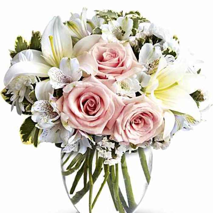 Pink roses and white lilies arranged in a clear glass vase