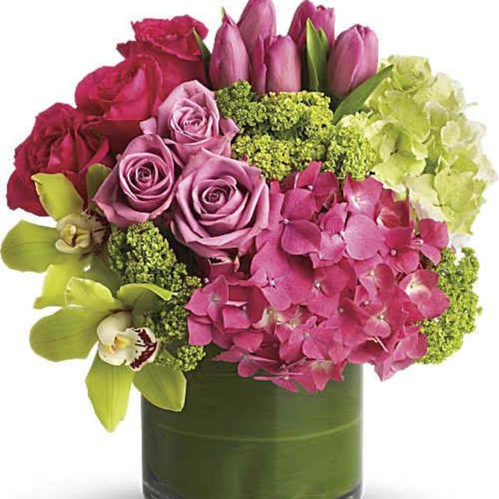 Pink roses and orchids arranged in a green glass vase