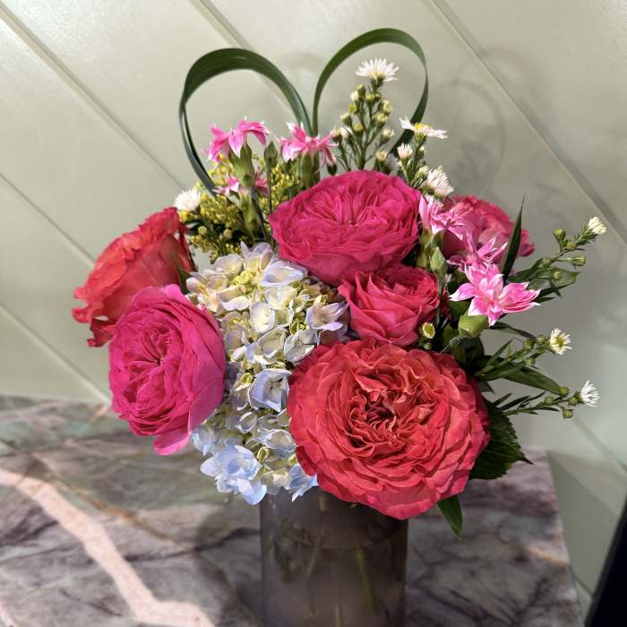 Pink roses and hydrangea in a dark glass vase