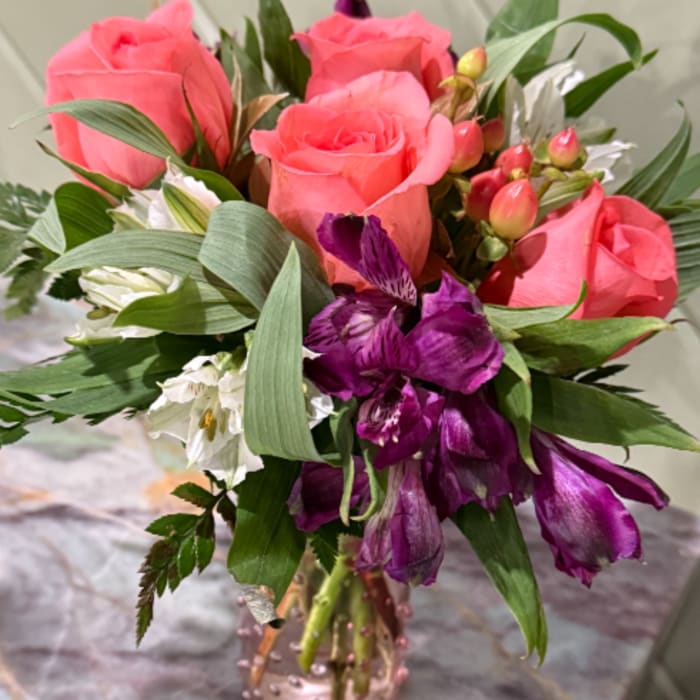 Pink roses and purple flowers in a glass vase