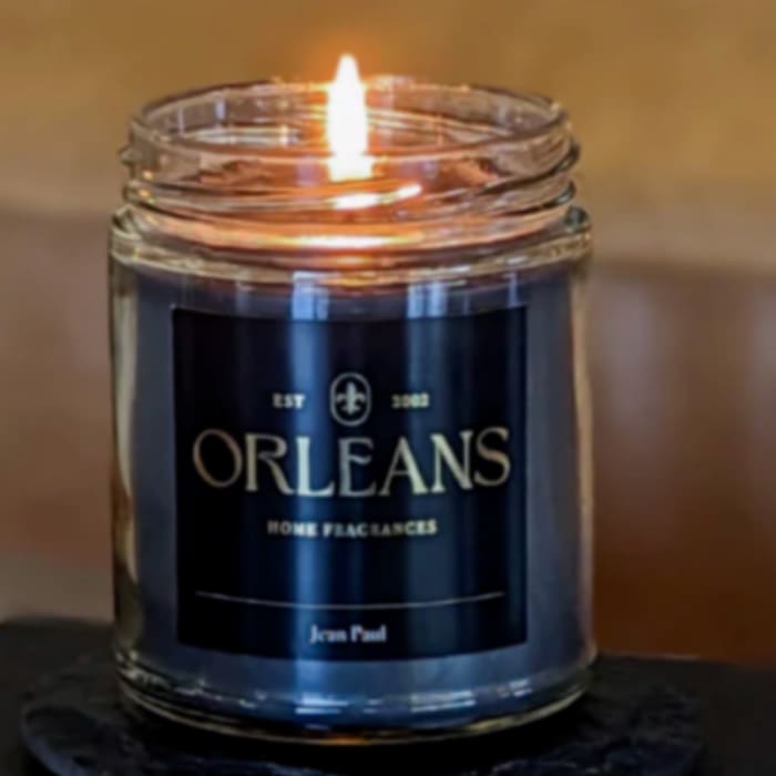 Lit candle in a glass jar with a dark label