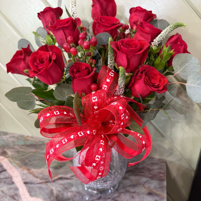 Bouquet of red roses in a glass vase with a red ribbon
