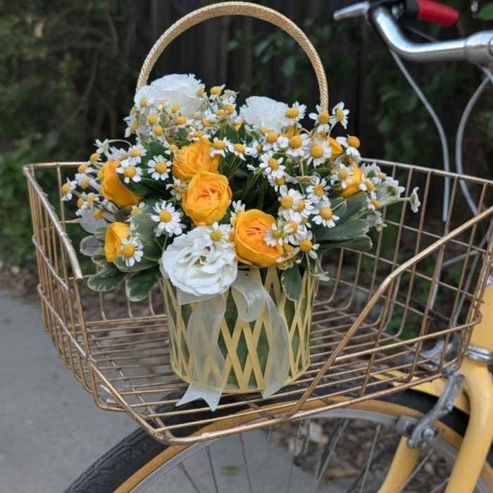 Yellow and white flowers in a basket on a bicycle front rack