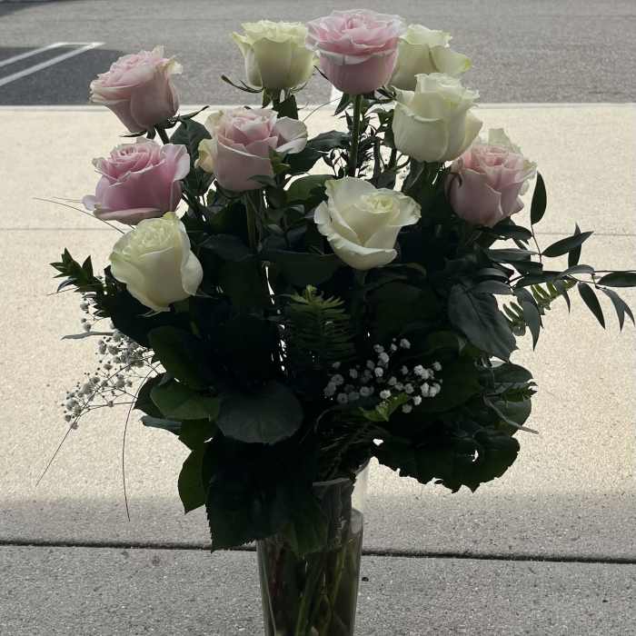 Pink and white roses arranged in a clear glass vase