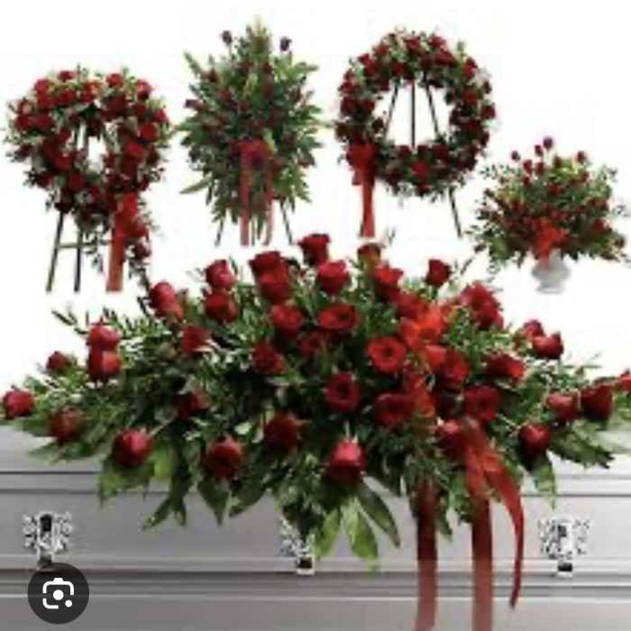 Red rose funeral sprays and wreaths arranged around a casket