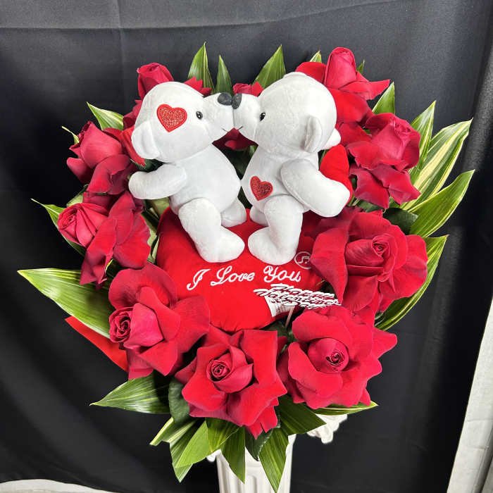 Red rose arrangement with two white teddy bears and a heart pillow