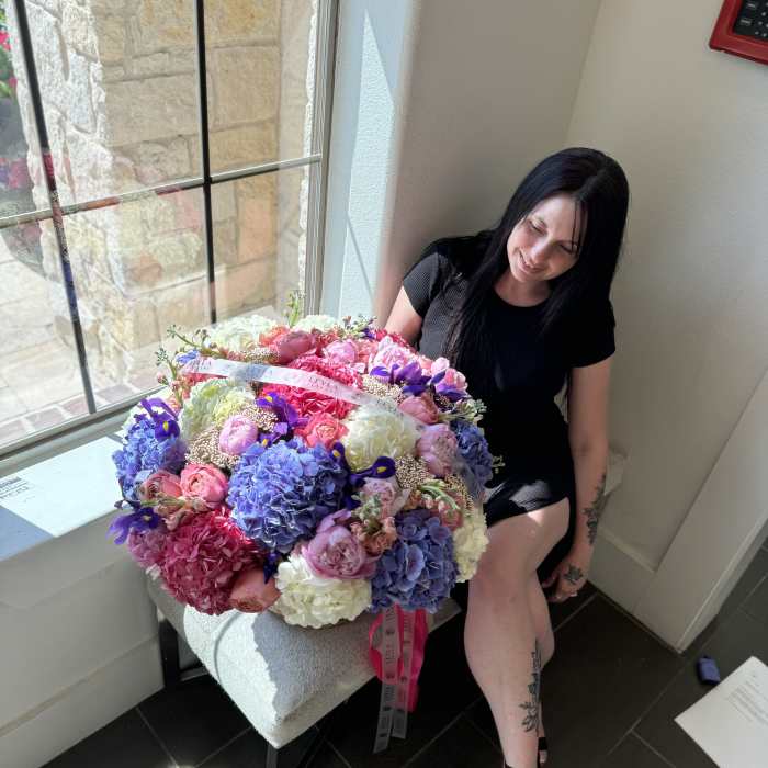 Large bouquet of pink, purple, and white flowers held by a seated woman
