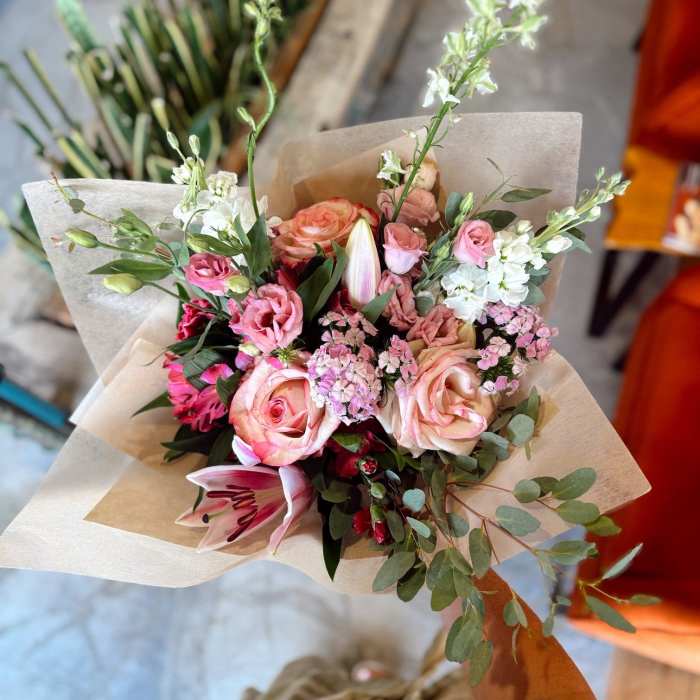 Hand-tied bouquet of pink and white flowers wrapped in paper