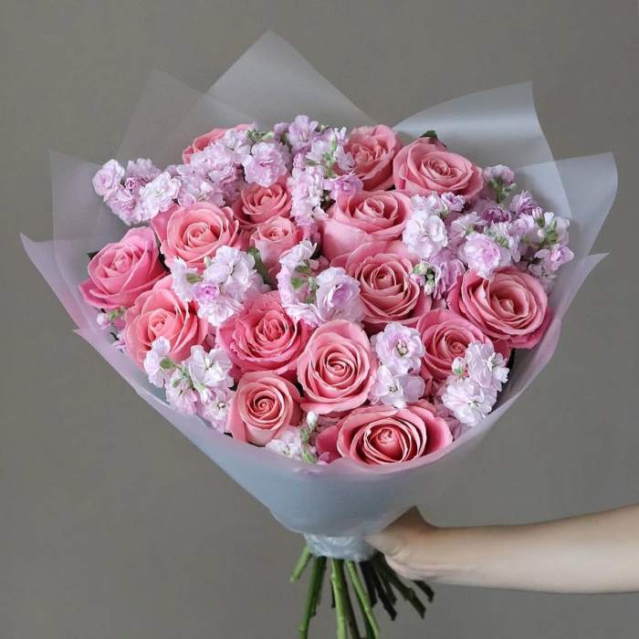 Pink rose bouquet with pale filler flowers wrapped in translucent paper