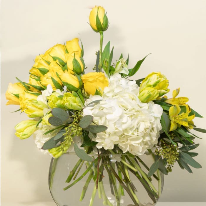 Yellow roses and white hydrangeas in a clear glass vase