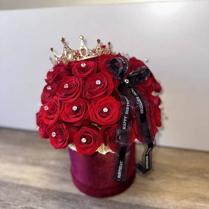 Red rose arrangement in a velvet box with a crown and birthday ribbon