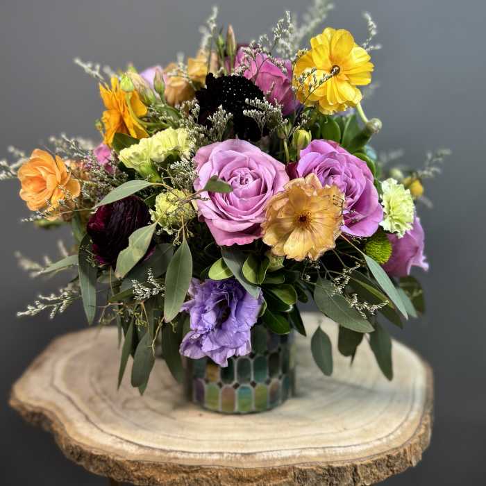 Mixed bouquet of roses and colorful blooms in a patterned vase